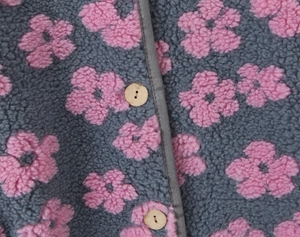 Macro detail of floral fleece fabric with soft lamb velvet texture and wooden button
