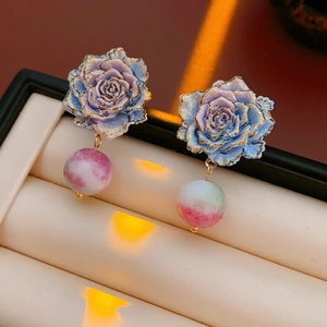 Gros plan de boucles d'oreilles rose avec paillettes dorées et perle dégradée