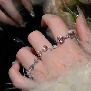 Set of silver heart and bow rings with pink zircon stones worn on fingers