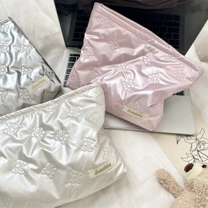 Detailed view of quilted PU bow pattern makeup bags in pink, silver, and white colors