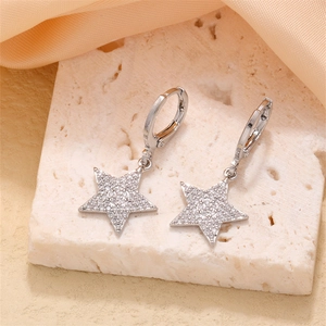 Silver star drop earrings with sparkling cubic zirconia on textured stone background
