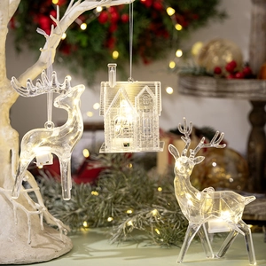 Detail of warm LED glowing acrylic reindeer and house hanging ornament for Christmas decor
