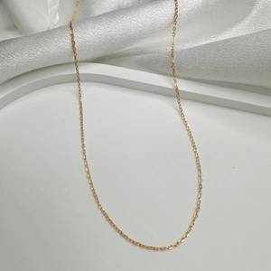 Close-up of minimalist gold plated S925 sterling silver chain necklace on white satin
