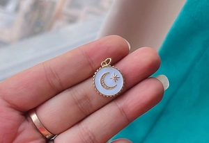 Close-up of a gold star and moon celestial charm held between fingers for size reference