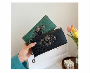 Detail of crocodile embossed long wallet with gothic metal skull hardware and card slots