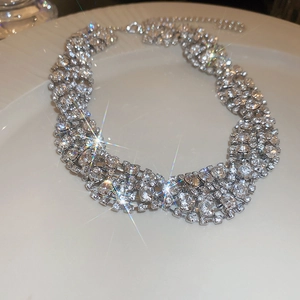 Macro detail of silver choker necklace with shimmering diamonds on a ceramic plate