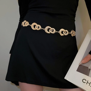 Detail of gold rhinestone interlocking geometric waist chain on a black dress