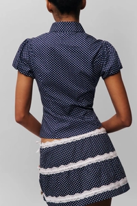 Detail of navy blue polka dot short sleeve shirt and ruffled skirt with white lace trim