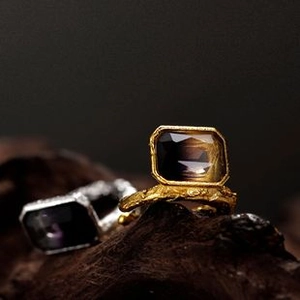 Macro shot of vintage irregular rings with square dark stones in gold and silver finish
