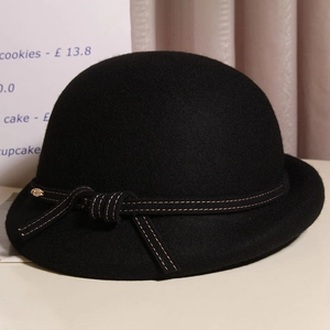 Detail of black wool felt cloche hat with a bow ribbon and golden bead accent