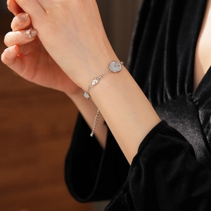 Macro detail of silver starburst bracelet with blue gemstone on model's wrist