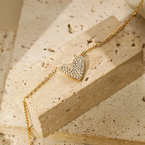 Close-up of gold-plated heart bracelet with zircon stones on natural stone blocks