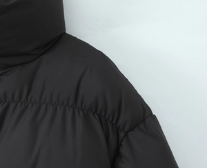 Detail shot of black puffer jacket shoulder and collar with premium matte texture