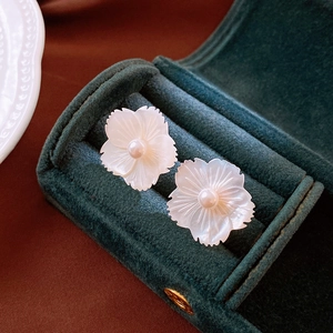 Elegant white shell flower stud earrings with pearl centers on green velvet jewelry box