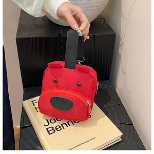 Detail of red cartoon bear handbag with zipper and black handles held by a model