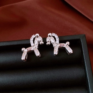 Detailed macro view of silver balloon dog earrings with zircon stones and logo