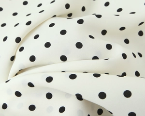 Dettaglio del tessuto in chiffon bianco a pois neri con trama morbida e leggera