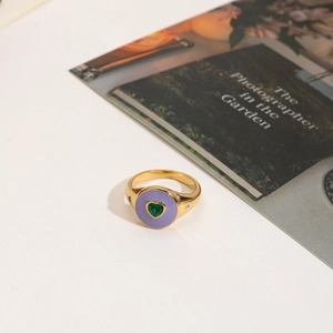 Detail of 18K gold stainless steel ring with purple enamel and green heart zircon