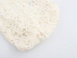 Gros plan sur un élégant tissu en dentelle blanc crème aux motifs floraux et maille fine