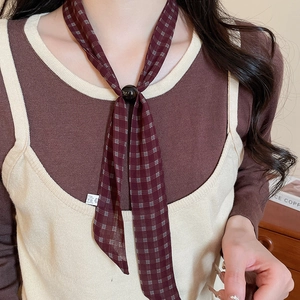 Detail of a dark red plaid chiffon scarf necklace featuring a black circular buckle closure