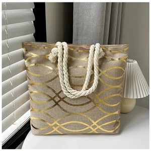 Detail of linen tote bag with golden wave patterns and white braided rope handles
