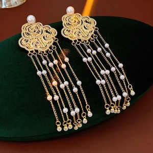 Close-up of gold pearl tassel earrings with auspicious cloud motifs on green velvet
