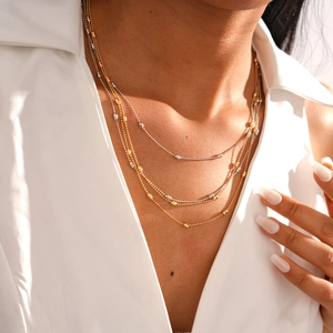 Layered gold and silver bead necklace on model featuring elegant oval metallic strands