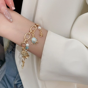 Close-up of gold ocean bracelet with turtle, starfish charms and pearls on a wrist