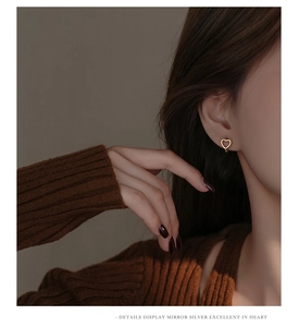 Detailed view of a model wearing minimalist gold hollow heart earrings in S925 sterling silver