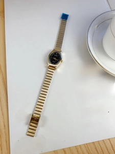 Detail of elegant gold quartz watch with black oval dial on a white magazine background