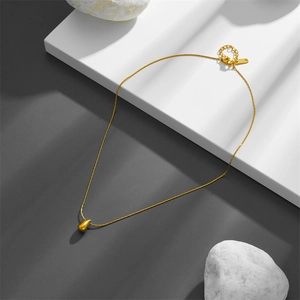 Polished gold teardrop pendant necklace in titanium steel on minimalist stone display