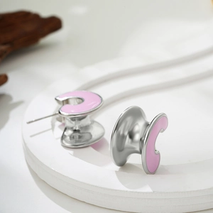 Minimalist C-shaped stainless steel earrings with matte pink enamel on white stone stand