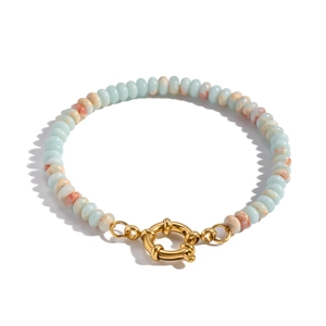 Close-up of light blue patterned beads with a gold spring ring clasp on white background