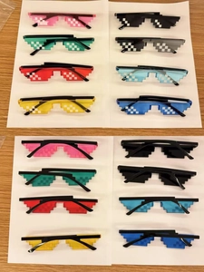 Flat lay of pixel-style party sunglasses in eight vibrant colors on a wooden surface