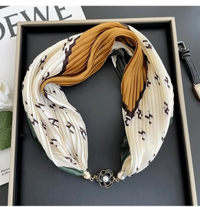 Macro detail of pleated silk scarf with H-pattern and pearl flower magnetic clasp