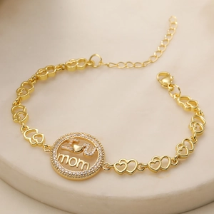 18K gold plated MOM bracelet with zircon heart links on marble tray background