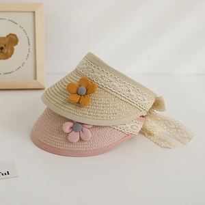 Detail of children's straw sun visors with delicate lace edges and floral accents