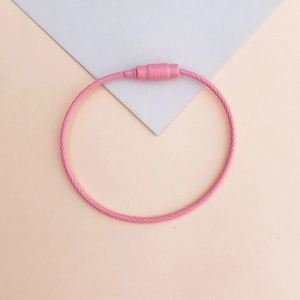 Pink vinyl-coated wire keychain ring with screw connector on modern geometric background