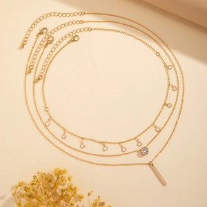 Close-up of triple-layered gold necklace with clear rhinestones and geometric pendants