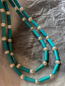 Detail of 18K gold plated necklace with turquoise beads and pearls on textured paper
