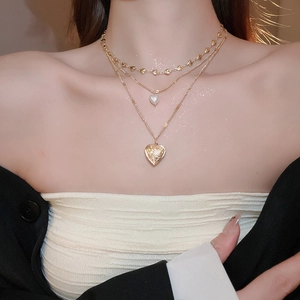 Detailed close-up of a triple-layered necklace with pearl and gold heart pendants