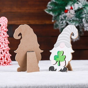 Detail view of wooden gnome ornament with striped hat holding a green clover leaf