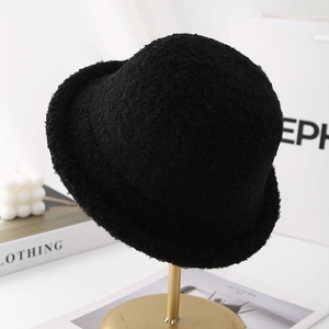 Detail of black faux shearling cloche hat with textured boucle finish on a display stand