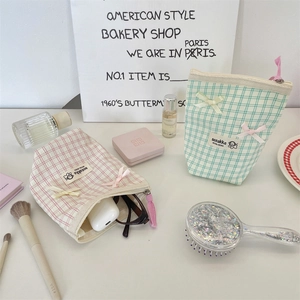 Detail of plaid makeup bags with bow decoration and spacious interior for toiletries