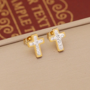 Macro detail of cross earrings featuring two-tone gold and silver finish with inlaid rhinestones