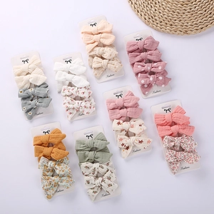 Set of four fabric bow hair clips for kids in floral and solid patterns on white background