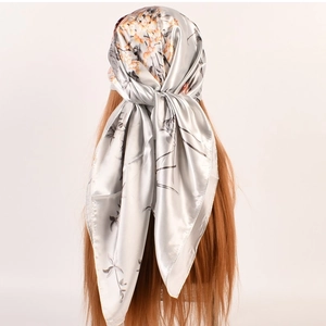 Dettaglio di un foulard quadrato in raso argento con stampa floreale arancione su modella
