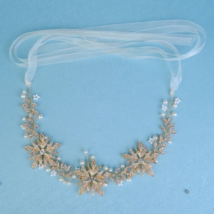 Macro shot of bridal headband with golden alloy leaves, white pearls and sparkling crystals