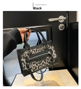 Detalle del bolso de leopardo con ribete de cuero negro y cremallera metálica decorativa