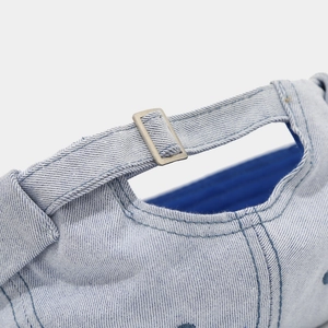 Detail of adjustable silver metal buckle on light blue denim brimless docker hat